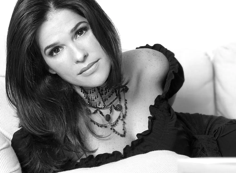 Retrato — mujer reclinada con joyería statement, blanco y negro